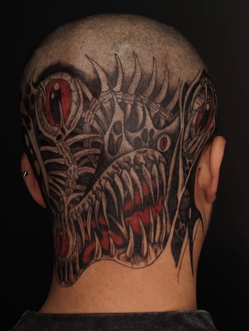 Completed tattoo on the back of the head and neck: a creature of bony ribs and rows of fangs with red eyes, in dotwork black and red