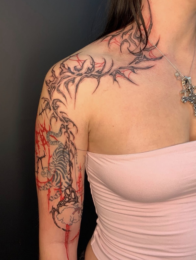 Completed tattoo on the shoulder and arm: spiky black ornamental linework with red accents running down to a tiger